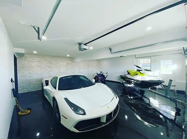 Home garage with a deep black gloss epoxy floor, a white sports car parked on it