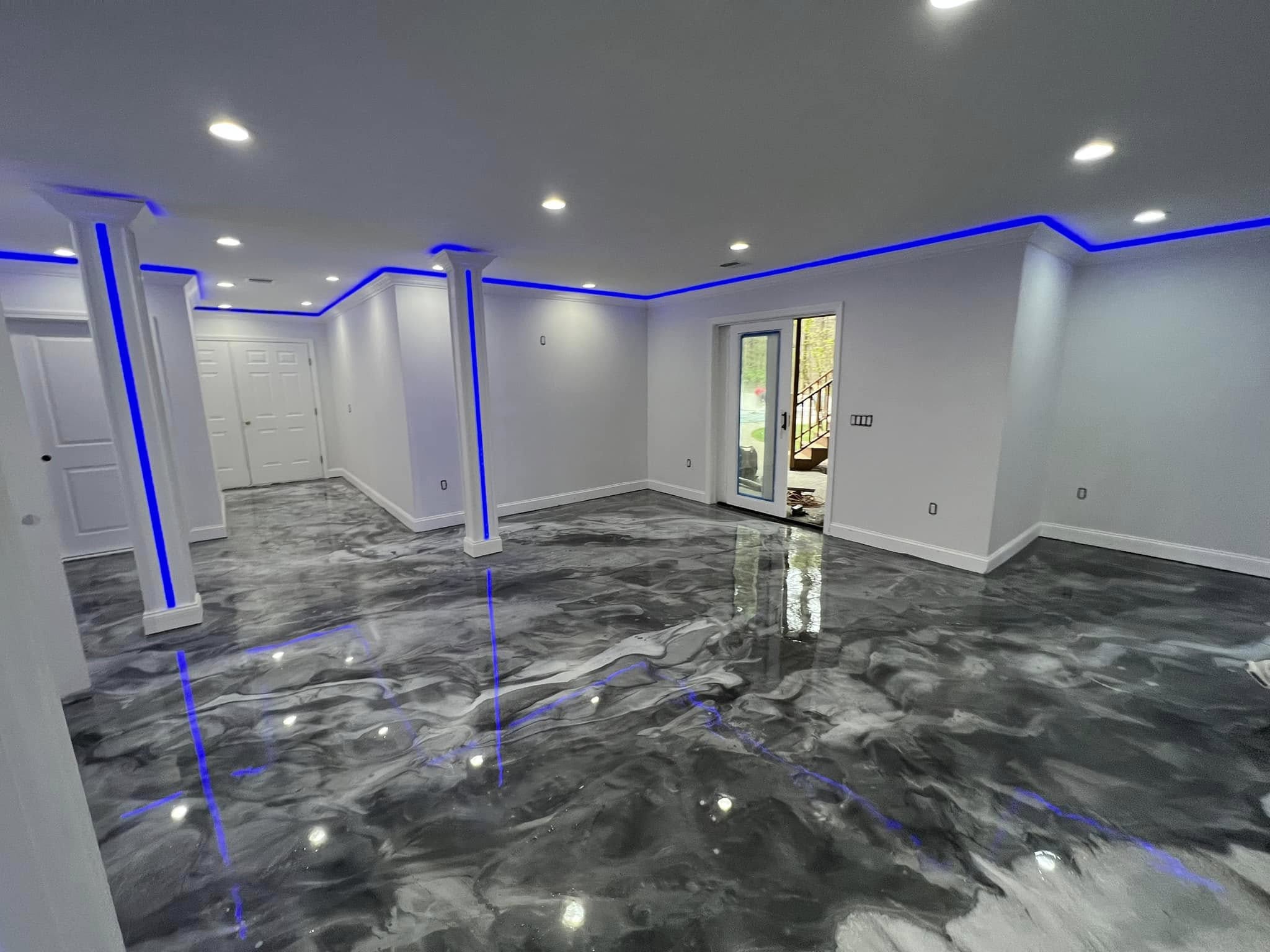 Residential basement with a grey metallic epoxy floor reflecting blue accent lighting